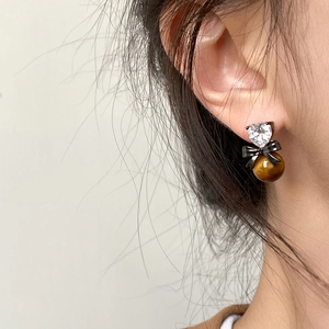 Detail view of heart zircon earrings with black bow and tiger eye stone bead
