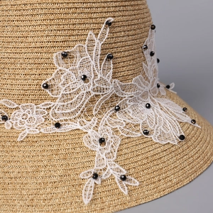 Elegant wide brim straw hat with white lace floral appliques and black bead details
