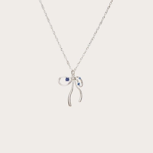 Detail of silver bow pendant necklace featuring sparkling blue round zircon stones