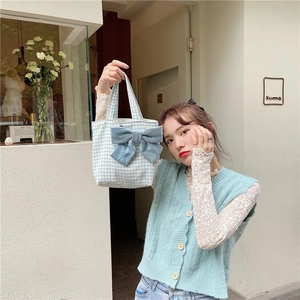 Detail of blue plaid lunch bag featuring a large bow and soft cotton fabric texture