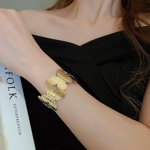 Detailed view of golden butterfly open cuff bracelet with textured metallic wings