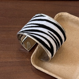 Détail de la manchette large à motif zèbre avec intérieur en métal argenté poli