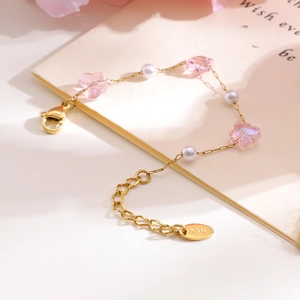 Macro detail of gold plated bracelet featuring pink butterfly beads and white pearls