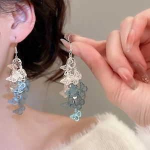 Détail de boucles d'oreilles papillon ajourées avec pampilles en dégradé bleu-argent