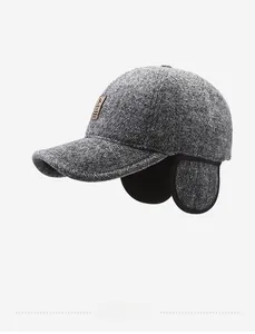 Detail view of grey herringbone tweed winter hat with earflaps and leather logo patch