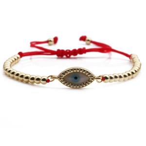Adjustable evil eye bracelet with gold beads, shell inlay, and red woven cord