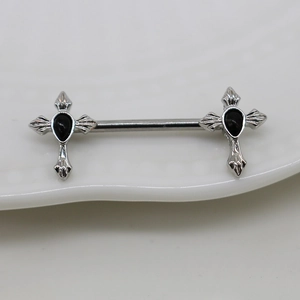 Macro detail of silver barbell piercing with cross ends and black teardrop gemstones