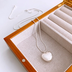 Gros plan détaillé d'un pendentif cœur en argent brossé sur une fine chaîne serpentine