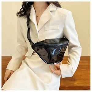Close-up of black glossy patent leather chest bag with zipper and adjustable strap