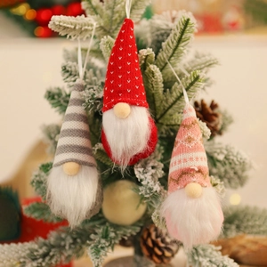 Knitted Christmas faceless gnome hanging ornaments on snowy tree for holiday decor