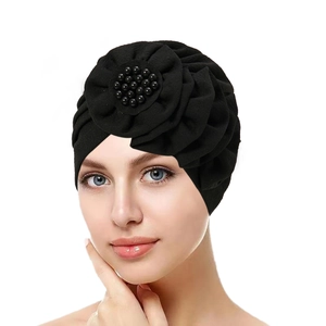 Close-up of black pleated turban hat with 3D flower and elegant pearl embellishments
