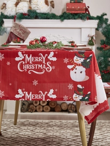 Detail van het rode kersttafelkleed met sneeuwpoppatronen en feestelijke kerstgroeten