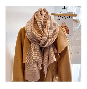 Detailed view of apricot pleated scarf with fine texture styled on a camel wool coat
