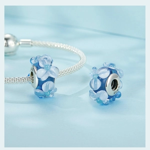 Macro detail of S925 silver core and blue glass charm with delicate flower patterns
