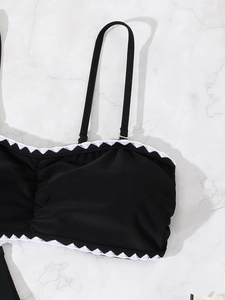 Detail of black bikini top with white scalloped embroidery and adjustable straps