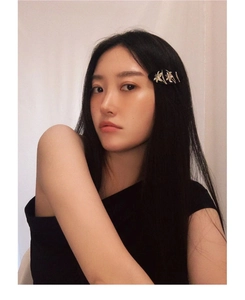 Close-up of a black side hair clip with silver floral decor worn on long dark hair