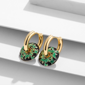 Details von goldenen Emaille-Ohrringen mit grünen Blumenmustern auf Schwarz