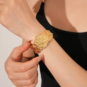 Dettaglio della trama lavica dorata irregolare e finitura martellata su un bracciale aperto