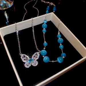 Detailed macro view of zircon butterfly pendant and blue cat-eye stone necklace