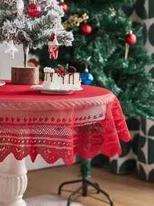 Detail of red hollow lace Christmas tablecloth with geometric floral texture and wavy edges