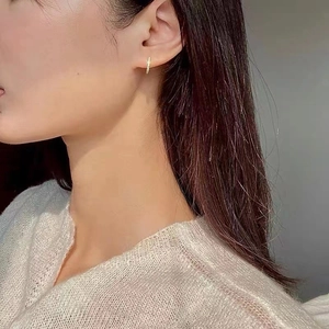 Close-up of a gold s925 silver hoop earring with paved white zircons on a model's ear
