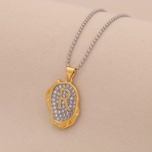 Macro shot of two-tone letter R pendant with sparkling rhinestones and golden texture