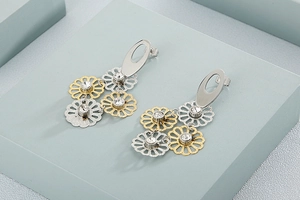 Detail of silver and gold bicolor daisy earrings with sparkling rhinestones decoration