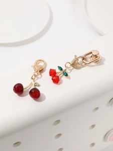 Detail view of red cherry charms featuring faceted rhinestones and green metal leaves
