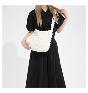 Detail view of white ruched bubble texture crossbody bag on a shoulder strap