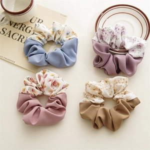 Close-up of four floral and solid fabric scrunchies in blue, pink, and purple colors