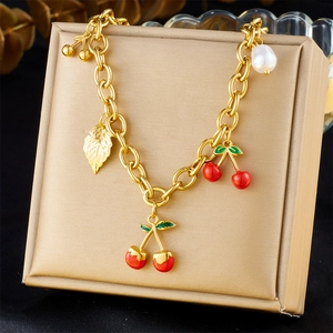 Detail of gold cherry pendant bracelet with red enamel fruit and white pearl accents