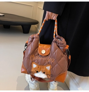 Detail of quilted brown tote bag with cat embroidery and houndstooth rope handle