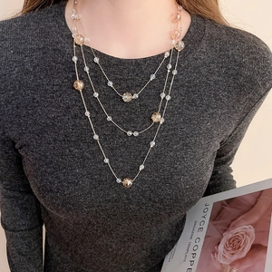 Close-up of elegant three-layer crystal beaded necklace with amber glass on dark sweater