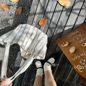 Close-up of black and white striped canvas tote bag on a rustic wooden deck