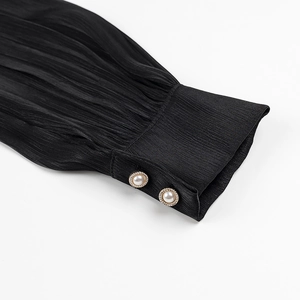 Detailed view of black pleated puff sleeve cuff with elegant gold-rimmed pearl buttons