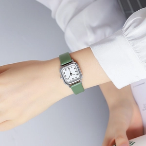 Close-up of minimalist square quartz watch with green leather strap on model wrist