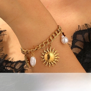 Detailed shot of a gold sun and moon charm bracelet with pearls on a wrist