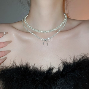 Close-up of double-layer pearl necklace featuring a sparkling zircon bow pendant
