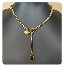 Detail of gold heart necklace with black oval pendant and OT toggle clasp on display