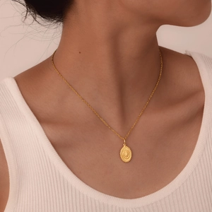 Detail of 18K gold-plated titanium sun pendant necklace worn on a female model