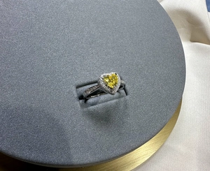 Macro shot of 6mm heart-cut yellow diamond ring with silver halo and side-stone pavé