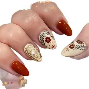 Almond shaped press-on nails with autumn floral patterns and caramel orange color
