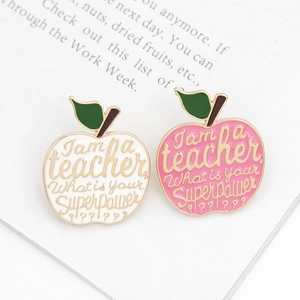 Cartoon apple-shaped enamel teacher brooches in pink and white with gold lettering