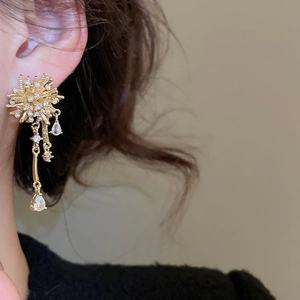 Close-up of gold fireworks earrings with pearls and cascading crystal tassels