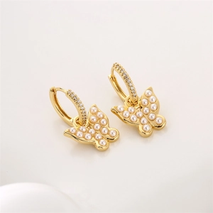 Macro detail of golden butterfly drop earrings with pearls and micro-pave crystals