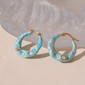 Detail of sky blue marble resin hoop earrings with gold plating and crystal accents