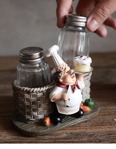 Detail of creative resin chef figurine holding cake with two glass seasoning shakers