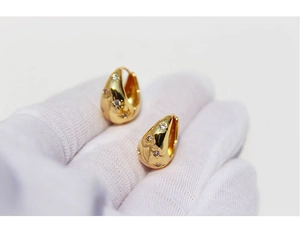 Macro shot of gold teardrop earrings with star engraving and micro-set zircon crystals