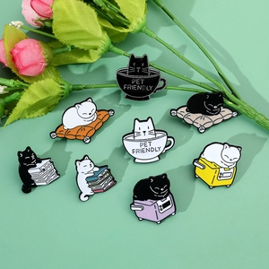 Flat lay of eight cute cartoon cat enamel pins in various poses on a light green background