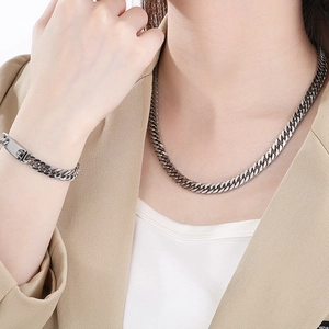 Close-up of silver stainless steel cuban link necklace and bracelet set on a model